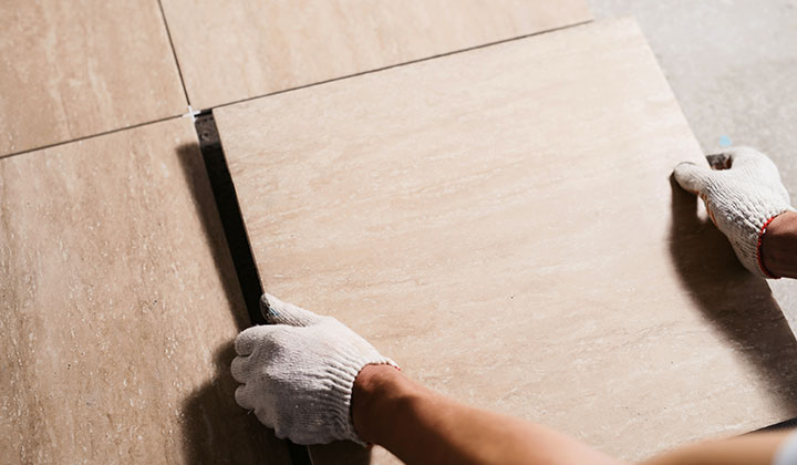 Tradesperson laying down tile over electric underfloor heating